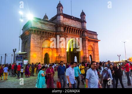 Mumbai, Maharashtra, India : la gente si raduna al crepuscolo intorno alla porta illuminata dell'arco monumentale dell'India costruito tra il 1913 e il 1924 nell'Indo-Sara Foto Stock