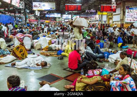 Mumbai, Maharashtra, India : i viaggiatori aspettano i loro treni all'interno della stazione ferroviaria Chhatrapati Shivaji Terminus (ex Victoria Terminus) Foto Stock