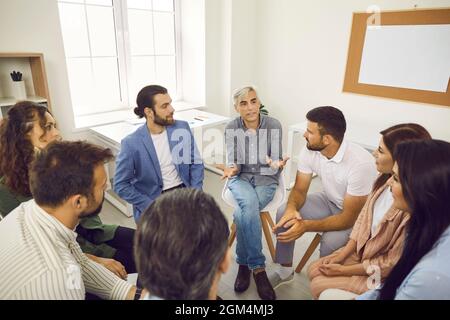 Coach senior che ha una conversazione con il team di uomini d'affari o dipendenti aziendali Foto Stock