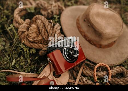 Primo piano di una macchina fotografica vintage, corde e un cappello marrone a terra Foto Stock