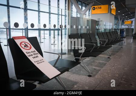 Cartello di avviso di distanza sociale sulle sedie del terminal dell'aeroporto. Misure di sicurezza da pandemia di covid-19 Foto Stock