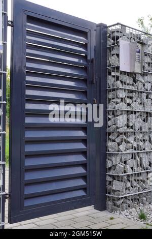 Porta d'ingresso con sistema di controllo accessi e citofono. Muro del Gabion. Foto Stock