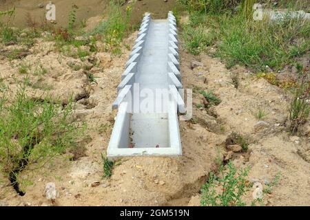 Costruzione dell'autostrada. Un sistema di moduli in calcestruzzo per lo scarico dell'acqua in eccesso dal manto stradale. Foto Stock