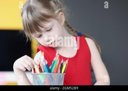 Bambina che sceglie matite multicolore da vetro Foto Stock