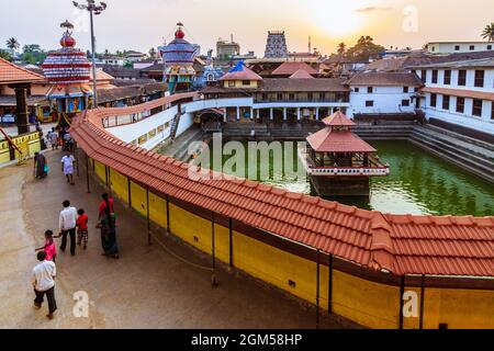 Udupi, Karnataka, India : la gente cammina al tramonto intorno al serbatoio d'acqua di Madhva Sarovara adiacente al tempio di Krishna 13 ° secolo fondato dal locale Foto Stock