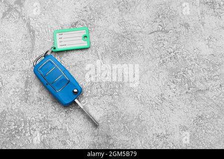 Chiave auto blu con etichetta in plastica su sfondo grunge Foto Stock