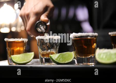 Barista che versa la gustosa tequila in bicchieri al tavolo al bar Foto Stock