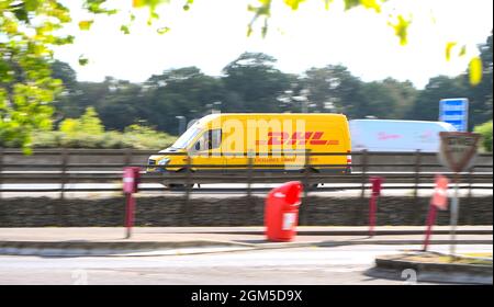 Un furgone DHL che guida sulla M27near Southampton fuori sulle consegne girato come un colpo di panning con movimento. Foto Stock