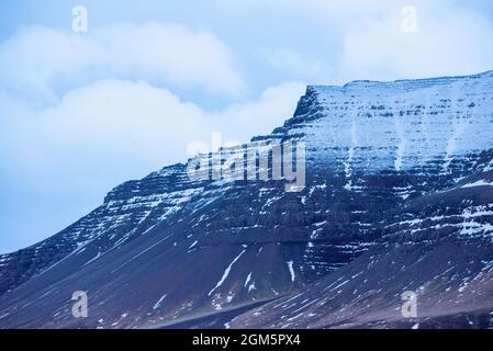 Creste nere di montagna innevate in Islanda con nuvole per aggiungere profondità. Foto Stock