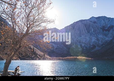 Lone persona gode di solitudine nel maestoso paesaggio alpino lago al tramonto Foto Stock