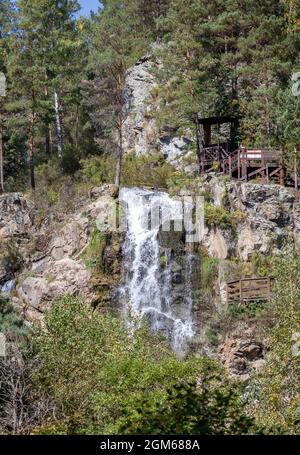 Primo piano di una potente cascata di alta qualità. Vista laterale di una cascata soleggiato nella natura selvaggia. Un grande flusso d'acqua si riversa verso il basso dal monte Foto Stock