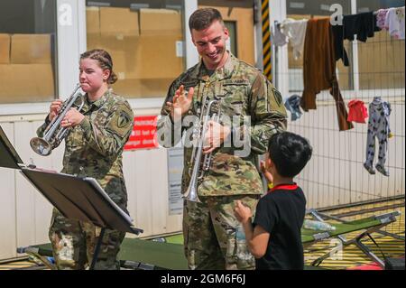 Sergente Robert Chambers, US Army EU corda e Africa Band e Chorus onde musicista a un bambino a Ramstein Air base, Germania, 24 agosto 2021. La USAEUR AF Band & Chorus ha supportato Operations Allees Refuge fornendo intrattenimento agli sfollati mentre si trovano in una sistemazione temporanea alla base aerea di Ramstein. (STATI UNITI Air Force foto di Senior Airman Jan K. Valle) Foto Stock