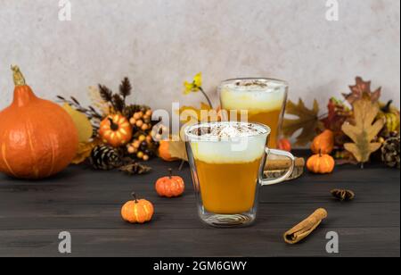 Spice latte di zucca, di stagione, dolce, calda bevanda autunnale. Frullato con panna montata. Sfondo in legno Foto Stock