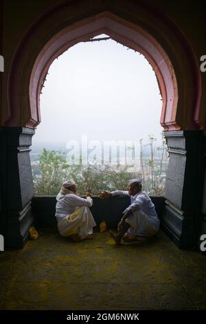 Due uomini seduti al di fuori del famoso e bellissimo tempio di Khandoba a Jejuri durante la festa di Somvati Amavasya Foto Stock