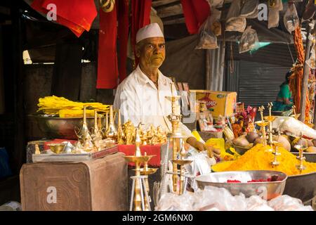 Un negoziante che vende articoli di puja fuori dal famoso e bellissimo tempio di Khandoba a Jejuri durante il festival di Somvati Amavasya Foto Stock