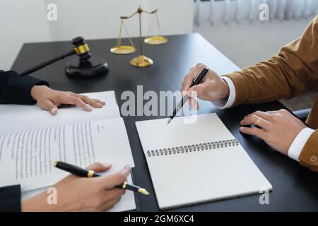 legge, scala di libra e martello sul tavolo, 2 avvocati stanno discutendo su carta contrattuale, la determinazione delle questioni di legge, mostrando carta e note. Foto Stock