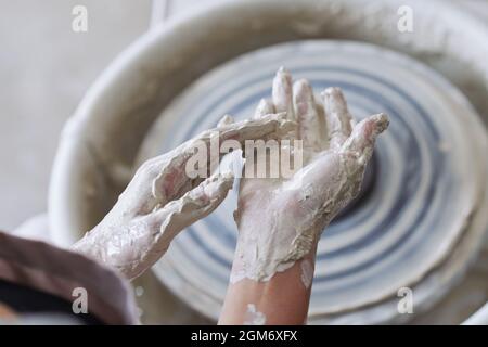 Mani di ceramista coperto in argilla dopo aver lavorato su vasai ruota Foto Stock