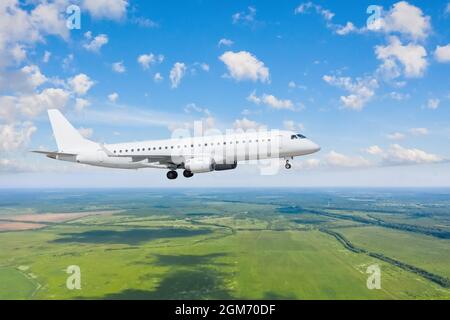 Volo aereo commerciale approccio con carrello di atterraggio esteso sopra il paesaggio nuvolato in luce solare di giorno Foto Stock