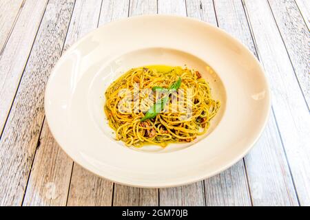Piatto di spaghetti all'aglio con cozze, prezzemolo e basilico su tavola di legno Foto Stock