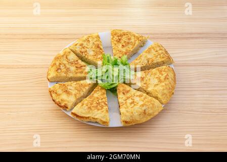 Frittata spagnola divisa in pezzi da servire con spiedini individuali su tavola di legno Foto Stock