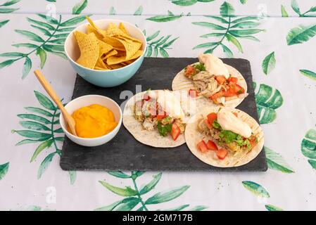 Menu messicano con tre tinga di pollo e nachos di mais in una ciotola per immergere con formaggio cheddar fuso Foto Stock