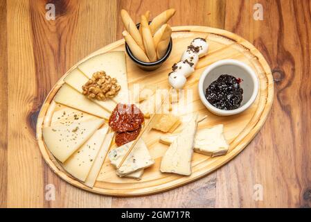 Tipica tavola di formaggi assortiti vista dall'alto con pomodoro secco, marmellata, noci e spike di pane Foto Stock