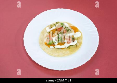 Taco con un sacco di coriandolo, salse varie, cipolla e Pico de gallo su un piatto bianco Foto Stock