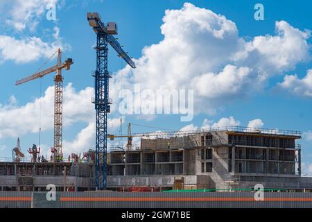 Costruzione di un edificio a più piani. Gru ad alta quota. Sfondo - cielo blu con nuvole. Foto Stock