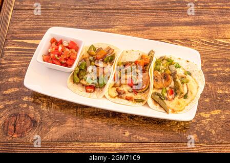 Tacos messicani di nopales, funghi e verdure con formaggio fundos e Pico de gallo su vassoio bianco Foto Stock