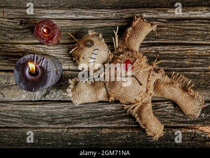 bambola voodoo mistica classica fatta di burlap per eseguire un rituale magico su un tavolo di legno ruvido alla luce di candele nere che bruciano Foto Stock