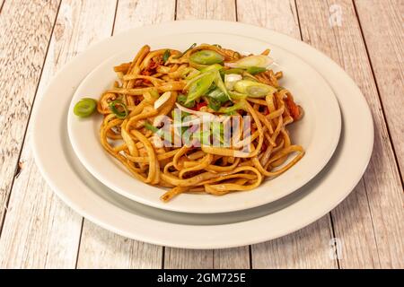 Tagliatelle saltate con verdure e pollo con erba cipollina tritata con salsa di soia cucinata da uno chef cinese Foto Stock