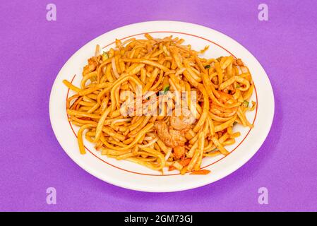 Piatto di noodle wok con carne di pollo, carota tritata, zucchine con pelle su sfondo viola Foto Stock