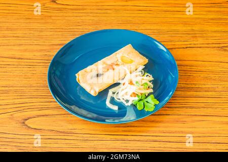 tamale farcito con verdure e uovo sodo guarnito con cipolla bianca cruda e prezzemolo su un piatto blu Foto Stock