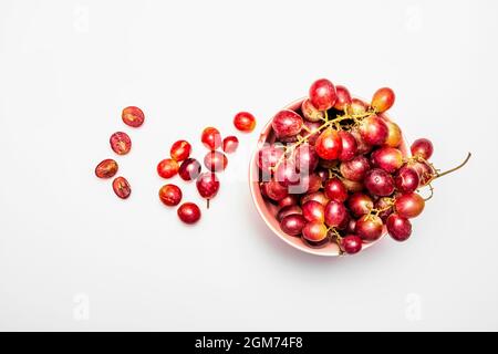 Grappoli di uve da dessert di colore garet in ciotola rosa su tavola bianca Foto Stock