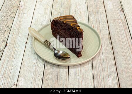 Porzione di deliziosa torta al cioccolato con un cucchiaio d'annata su un piatto grigio Foto Stock