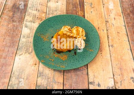 Dessert alla torta di mele con gelato alla vaniglia e tocchi di panna su un piatto bianco con cannella macinata Foto Stock