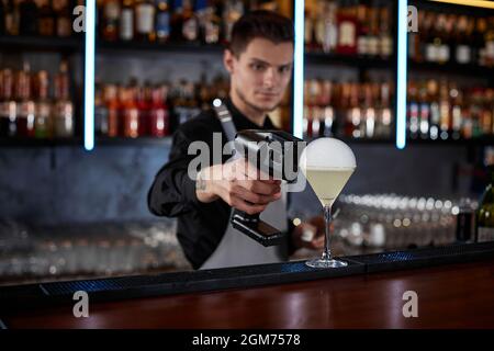 il barman sta facendo un cocktail con una bolla d'aria fumosa Foto Stock