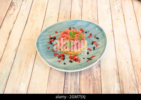 Tartare di tonno rosso su guacamole messicane e uova di pesce rosse e nere su un piatto blu Foto Stock