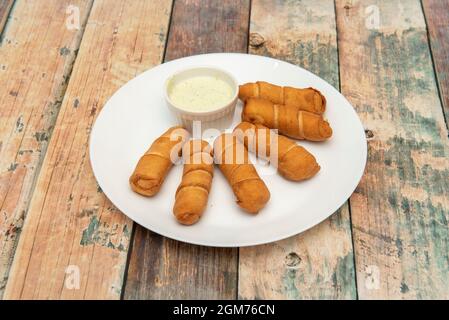 Porzione di tequeños venezuelano fritto e una piccola ciotola di salsa da immergere Foto Stock