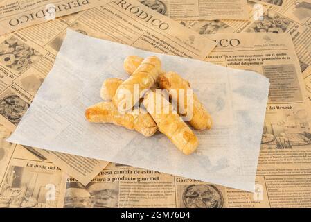 Una buona manciata di tequeños appena fatto ripieni su carta bianca cerata e giornale Foto Stock