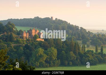 Il castello di Dunster e la Torre di Conygar si ammirano dal Dunster Park ai margini dell'Exmoor National Park, Somerset, Inghilterra. Foto Stock