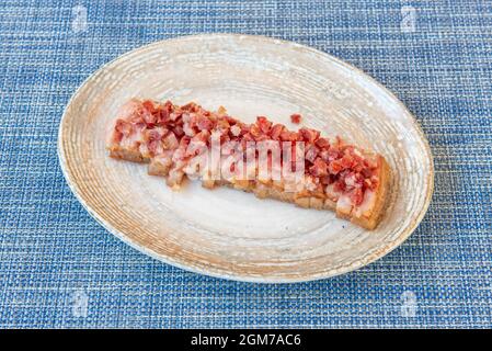 Piatto da cucina Techno-emotivo con torrezno e pezzi di prosciutto su maltel blu Foto Stock