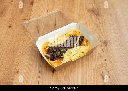 Omelette, patate fritte e salsicce di sangue con prezzemolo in un contenitore con coperchio di plastica per la consegna a domicilio Foto Stock