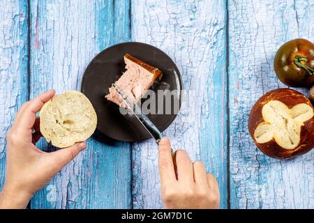 Vista dall'alto dell'immagine delle mani della donna che sparge la foie con un coltello su un rotolo fresco Foto Stock