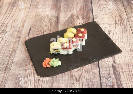 Sushi uramaki rotolo di tonno rosso e avocado maturo con salsa e wasabi con ginseng su ardesia nera Foto Stock