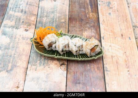 Sushi al salmone di Uramaki con alghe, queso philadelphia e guacamole a forma di ciotola verde e foglia di albero Foto Stock