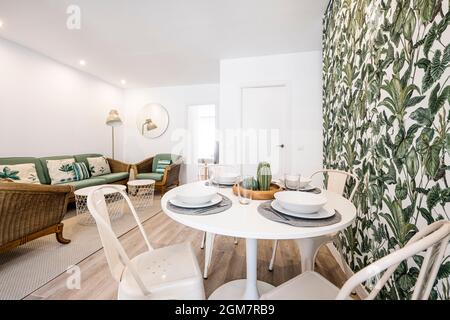 Piccolo tavolo da pranzo rotondo bianco con servizio set circondato da  accessori decorativi simili a piante e foglie in un appartamento affitto  per le vacanze Foto stock - Alamy