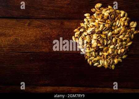 Vista dall'alto dei semi di zucca salati arrostiti su un tavolo di legno Foto Stock