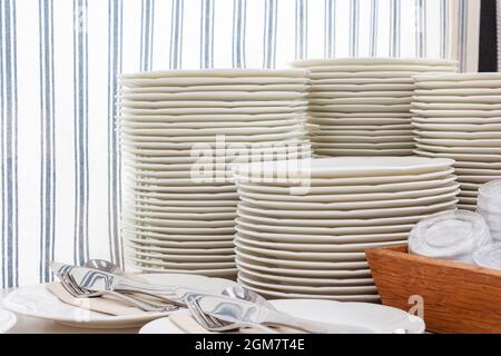 Pile di piatti bianchi puliti per catering a buffet nella sala ristorante Foto Stock