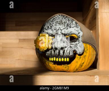 Maschera Spooky - un cranio su una zucca con una rosa gialla invece di un occhio. Simbolo dell'orrore del partito, decorazioni di Halloween. L'oggetto viene evidenziato Foto Stock